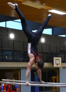 Patrick im Handstand auf dem Barren mit gegrätschten Beinen