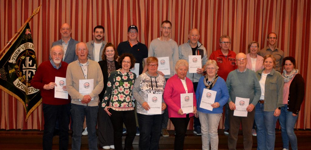 TuS Vorstand mit geehrten Mitgliedern neben der Vereinsfahne